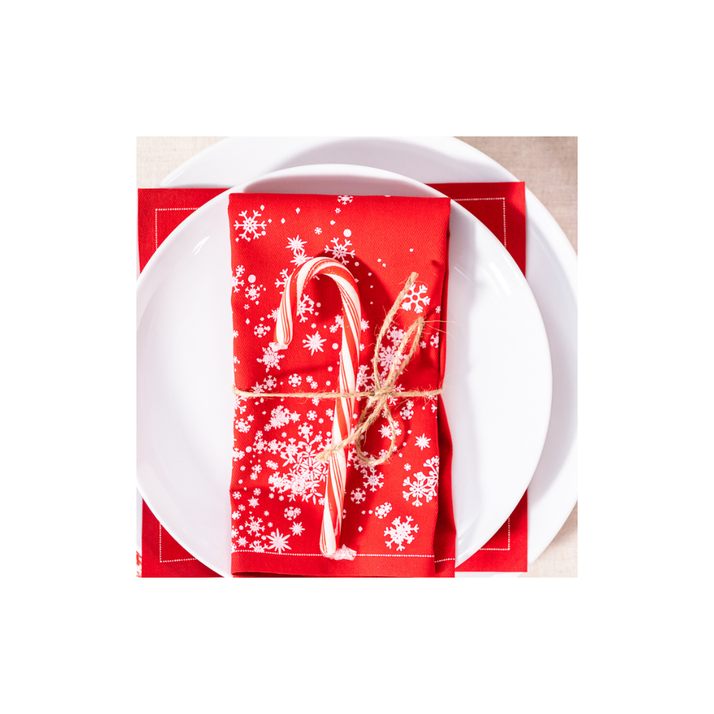 Toreador organic cotton napkin with white snowflake print, folded on a white plate with candy cane, festive table setting