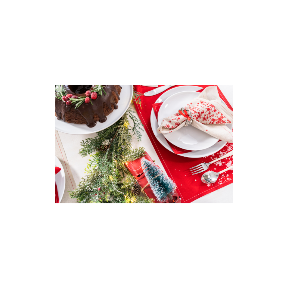 Holiday table setting with red and cream organic cotton napkin featuring snowflake print, white plates, cake, and festive greenery.