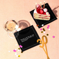 Black 30th birthday quote cocktail napkins styled with a birthday cake, wine glass, confetti, and gold “30” decoration, featuring the saying, “Welcome to 30! The age when you should know better, but really don’t.”