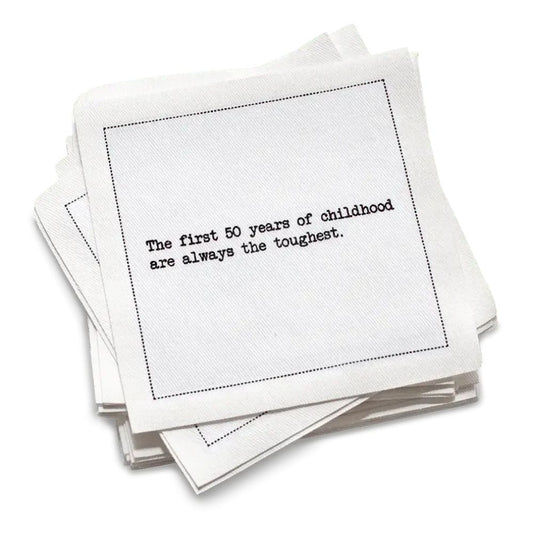 Organic cotton cocktail napkin with black dotted border printed with the quote "The first 50 years of childhood are always the toughest," from Five Star Napkins' 50th birthday quote collection