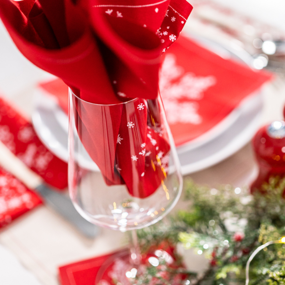 Persimmon organic cotton napkin with white snowflake print in wine glass on holiday table setting