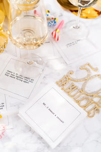 Organic cotton cocktail napkins with printed quotes, including '50:...I demand a recount!', styled for a celebration table setting with party decor and wine glasses.
