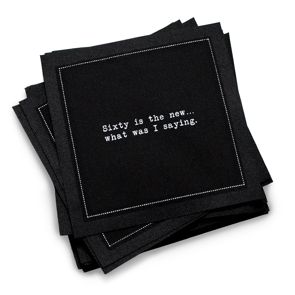 Organic cotton cocktail napkin, black, with white dotted border printed with the quote "Sixty is the new... what was I saying," from Five Star Napkins' 60th birthday quote collection