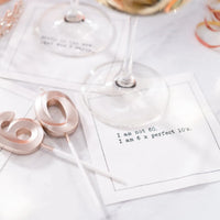 Organic cotton cocktail napkin printed with the quote "I am not 60. I am 6 x perfect 10's," styled on a marble table with rose gold "60" candles and wine glasses, from Five Star Napkins' 60th birthday quote collection
