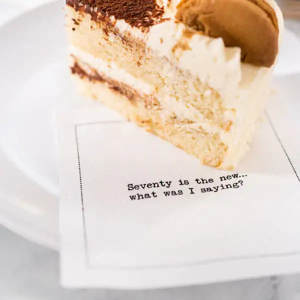 Slice of cake on an organic cotton napkin featuring quote 'Seventy is the new... what was I saying?'