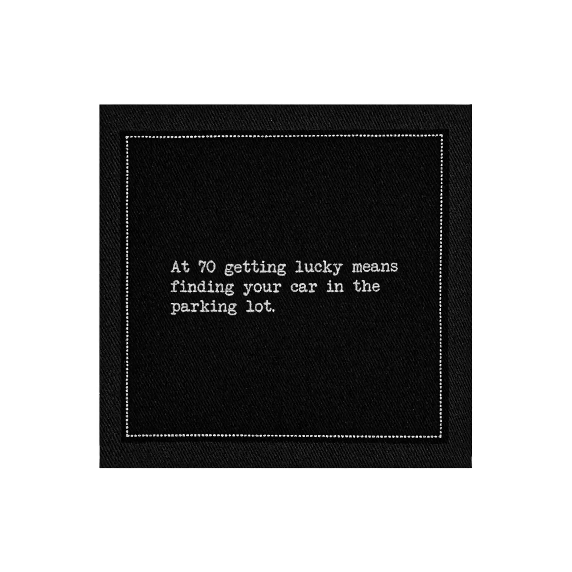 Anthracite Grey organic cotton napkin with printed quote: 'At 70 getting lucky means finding your car in the parking lot.'