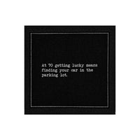 Anthracite Grey organic cotton napkin with printed quote: 'At 70 getting lucky means finding your car in the parking lot.'