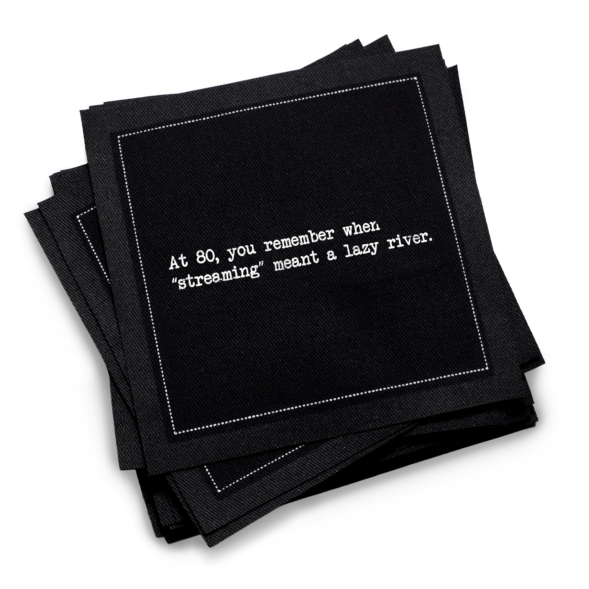Organic cotton cocktail napkin, black, with white dotted border printed with the quote "At 80, you remember when 'streaming' meant a lazy river,'" from Five Star Napkins' 80th birthday quote collection