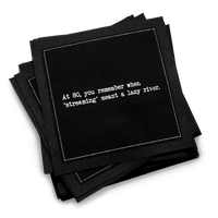 Organic cotton cocktail napkin, black, with white dotted border printed with the quote "At 80, you remember when 'streaming' meant a lazy river,'" from Five Star Napkins' 80th birthday quote collection