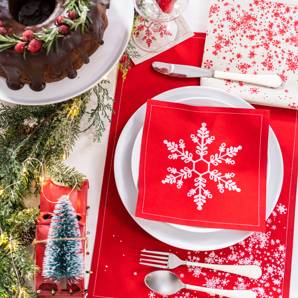 Holiday table setting with red Persimmon organic cotton napkin featuring white snowflake design