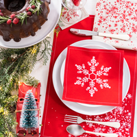 Holiday table setting with red Persimmon organic cotton napkin featuring white snowflake design