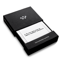 Open black gift box from Five Star Napkins' 90th birthday quote collection, revealing an organic cotton cocktail napkin printed with the quote "At 90, your dance moves are legally considered 'interpretive,'"