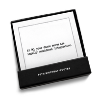 Black gift box from Five Star Napkins' 90th birthday quote collection, open to display an organic cotton cocktail napkin printed with the quote "At 90, your dance moves are legally considered 'interpretive,'"