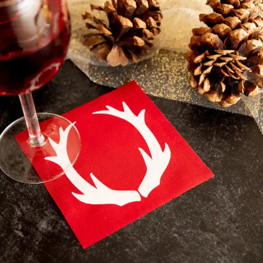 Persimmon organic cotton napkin with white antler print, wine glass, pine cones, holiday table setting