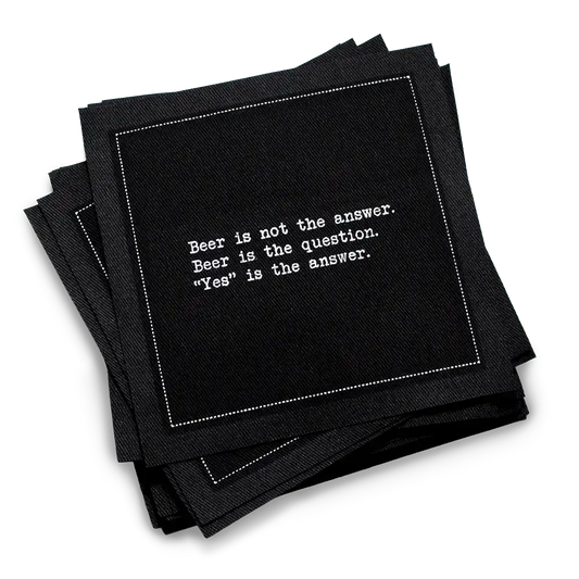 A stack of black Beer Quotes cocktail napkins printed with a white dotted border and the phrase, “Beer is not the answer. Beer is the question. ‘Yes’ is the answer.”