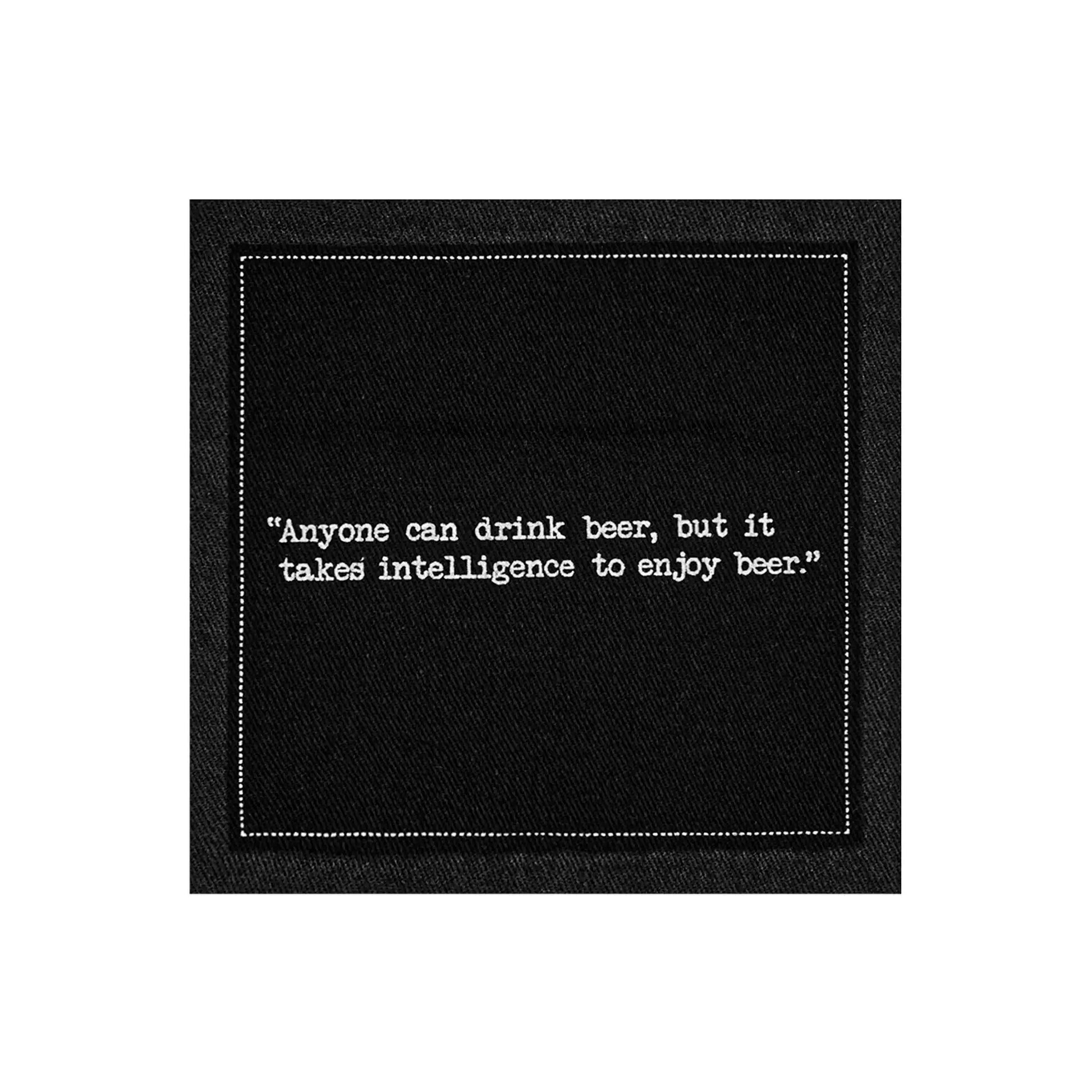A single black Beer Quotes cocktail napkin printed with a white dotted border and the phrase, “Anyone can drink beer, but it takes intelligence to enjoy beer.”
