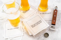 Glasses of beer sit on scattered white Beer Quotes cocktail napkins beside a bottle opener and bottle cap. Visible sayings include, “Save water…drink beer!” and “Never look at your beer as half empty; look at it as halfway to your next beer.”