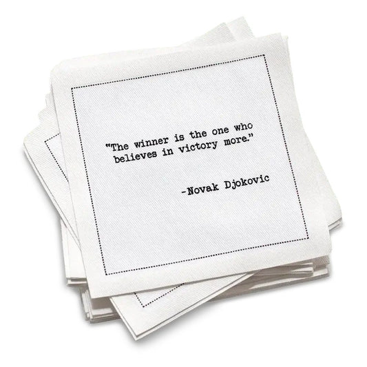 Stack of white cotton cocktail napkins with a black quote by Novak Djokovic on a white background