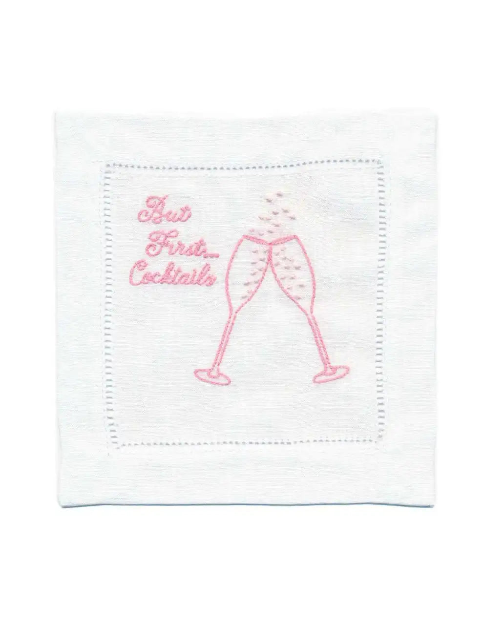 Organic cotton cocktail napkin with pink embroidery, featuring 'But First... Cocktails' quote and two glasses.