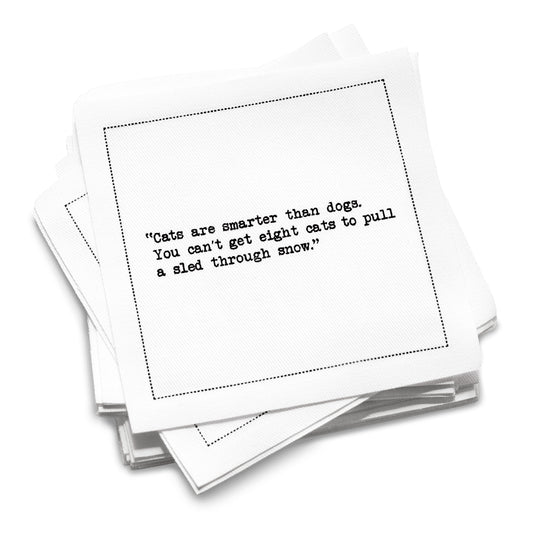 Stack of white organic cotton cocktail napkins with black dotted border printed with the quote “Cats are smarter than dogs. You can't get eight cats to pull a sled through snow,” from Five Star Napkins' Cat quote collection