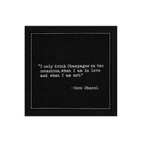 Organic cotton cocktail napkin, black, with white dotted border printed with the Coco Chanel quote "I only drink Champagne on two occasions, when I am in love and when I am not," from Five Star Napkins' Champagne quote collection