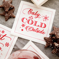 Organic cotton cocktail napkin with 'Baby it's COLD Outside' quote, holiday cookies, and glass