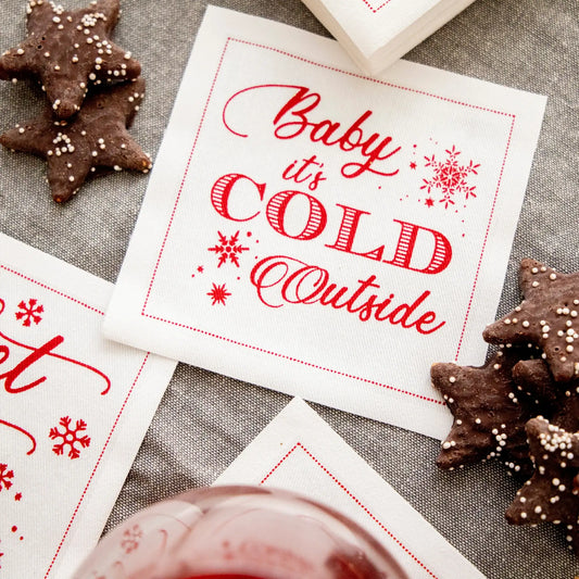 Organic cotton cocktail napkin with 'Baby it's COLD Outside' quote, holiday cookies, and glass
