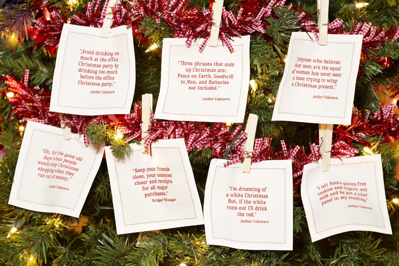 Organic cotton white cocktail napkins with printed Christmas quotes displayed on a Christmas tree.