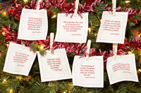 Organic cotton white cocktail napkins with printed Christmas quotes displayed on a Christmas tree.