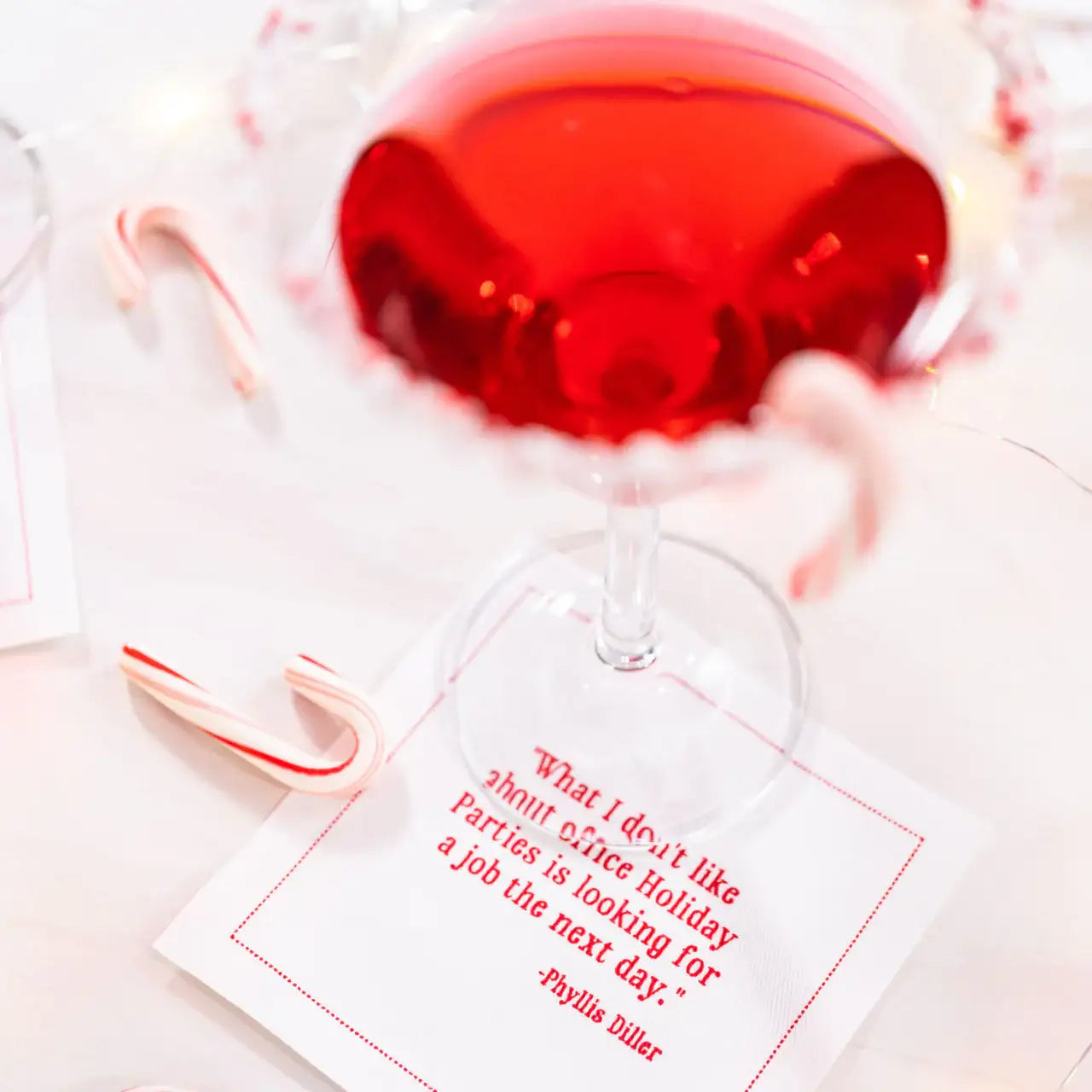 Organic cotton cocktail napkin with red quote, candy canes, and cocktail glass at a holiday setting