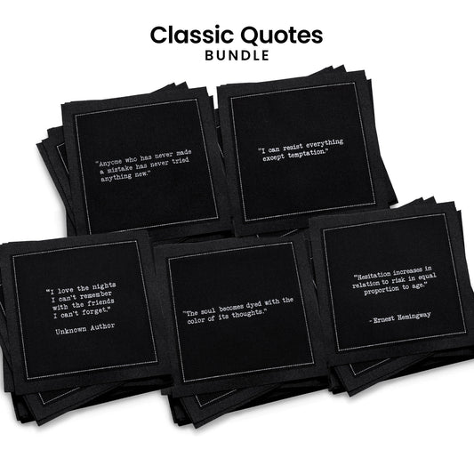 Stack of five organic cotton cocktail napkins, black, from Five Star Napkins' Classic Quotes Bundle, each printed with a different quote from the Oscar Wilde, Hemingway, Marcus Aurelius, Einstein, and Drinking Quotes collections