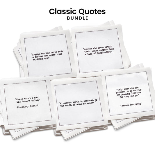 Stack of five organic cotton cocktail napkins from Five Star Napkins' Classic Quotes Bundle, each printed with a different quote from the Oscar Wilde, Hemingway, Marcus Aurelius, Einstein, and Drinking Quotes collections