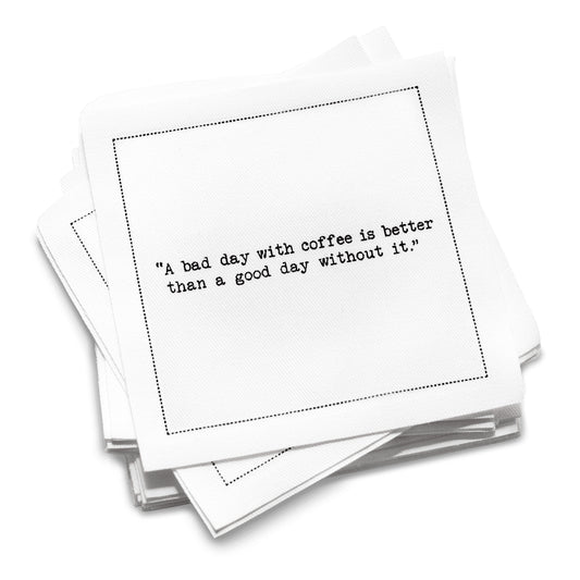 Organic cotton cocktail napkin with a black dotted border printed with the quote "A bad day with coffee is better than a good day without it," from Five Star Napkins' Coffee Quotes quote collection