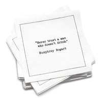 Stack of white drinking quote cocktail napkins with black typewriter-style text reading, “Never trust a man who doesn’t drink.” – Humphrey Bogart.