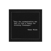 Black cocktail napkin with white typewriter-style text reading, “Only the unimaginative can fail to find a reason for drinking Champagne.” – Oscar Wilde.