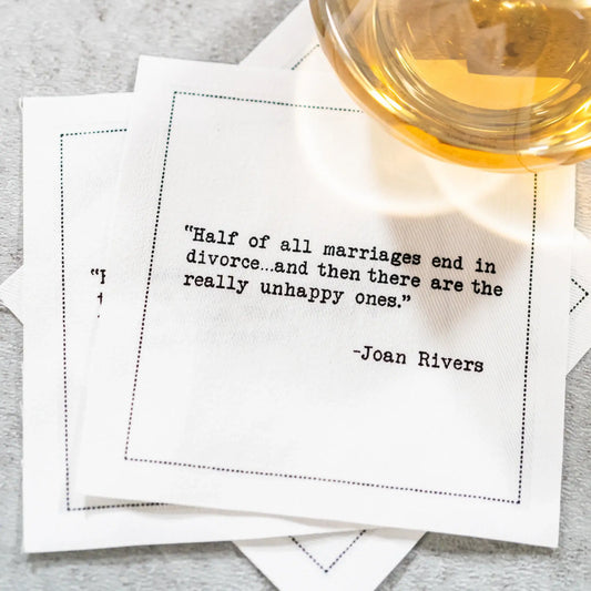 Organic cotton cocktail napkin printed with the Joan Rivers quote "Half of all marriages end in divorce…and then there are the really unhappy ones," styled next to a glass on a table, from Five Star Napkins' Divorce quote collection