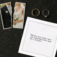 Organic cotton cocktail napkin printed with the quote "Whoever said money can't buy happiness never paid for a divorce," styled next to a torn wedding photo and two wedding rings, from Five Star Napkins' Divorce quote collection