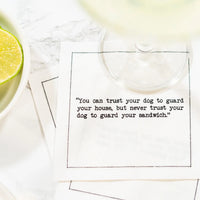 Organic cotton cocktail napkin with quote 'You can trust your dog to guard your house, but never trust your dog to guard your sandwich,' styled with a beverage and lime slice.