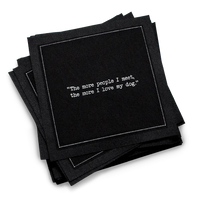 Stack of black organic cotton cocktail napkins with white dotted border printed with the quote “The more people I meet, the more I love my dog,” from Five Star Napkins' Dog quote collection