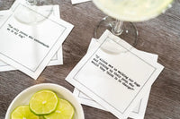 Organic cotton cocktail napkins with printed dog quotes on a wood table, drinks and lime slices nearby.