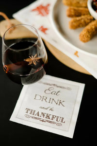 Organic cotton cocktail napkin with 'Eat Drink and be Thankful' quote, styled with wine and appetizers