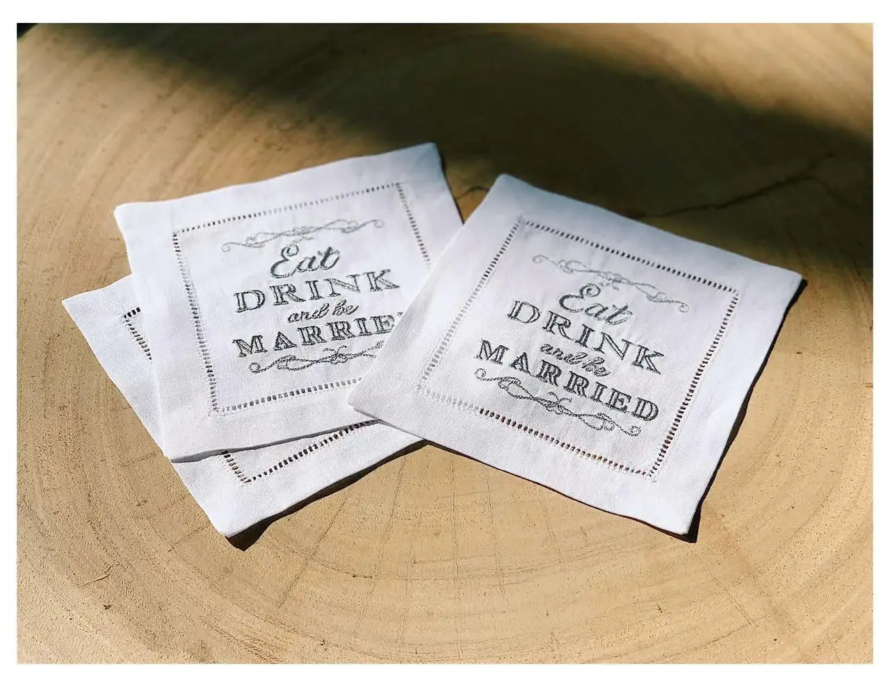 Organic cotton cocktail napkins with printed quote 'Eat Drink and be Married' on table.