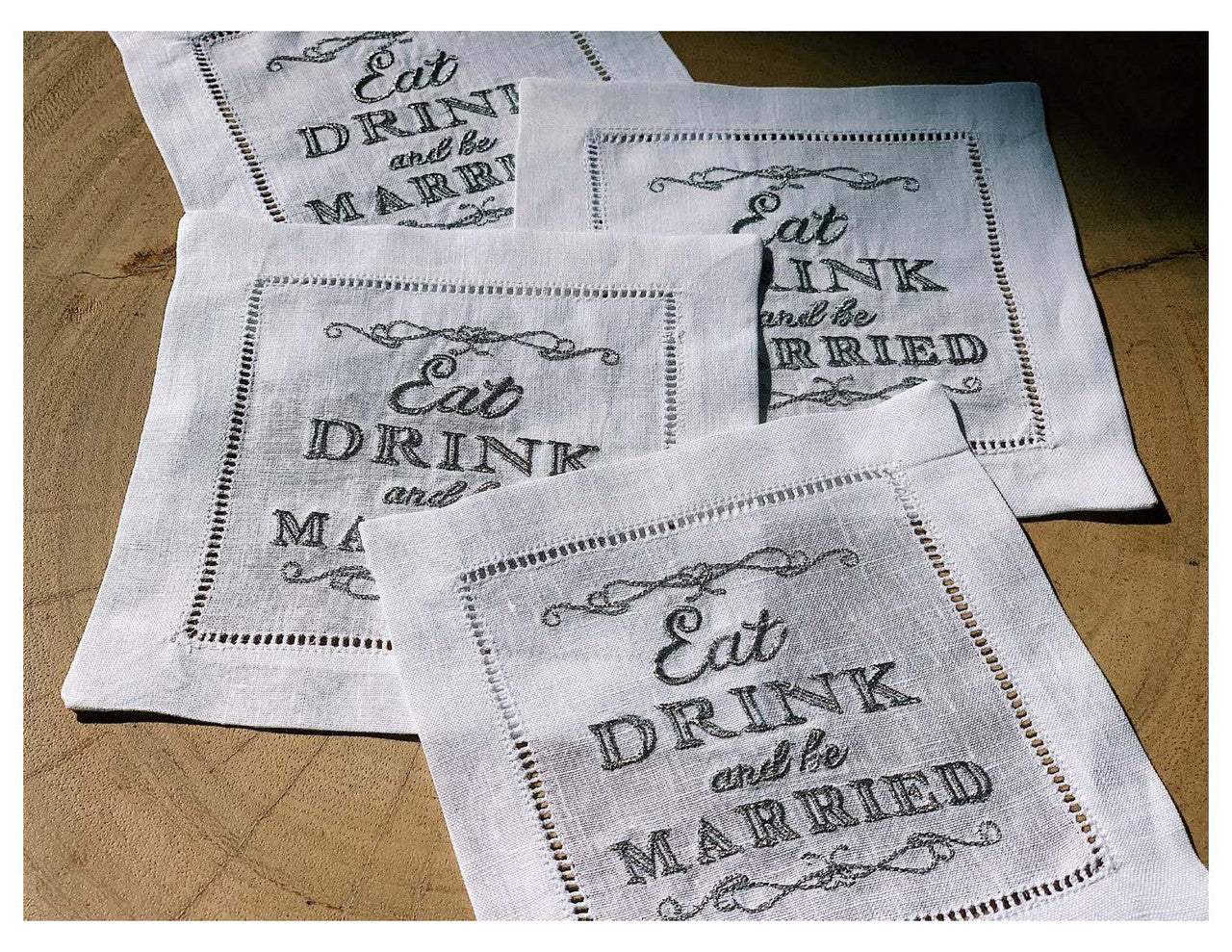 Set of organic cotton napkins with the printed quote 'Eat, Drink and be Married' on a wooden surface