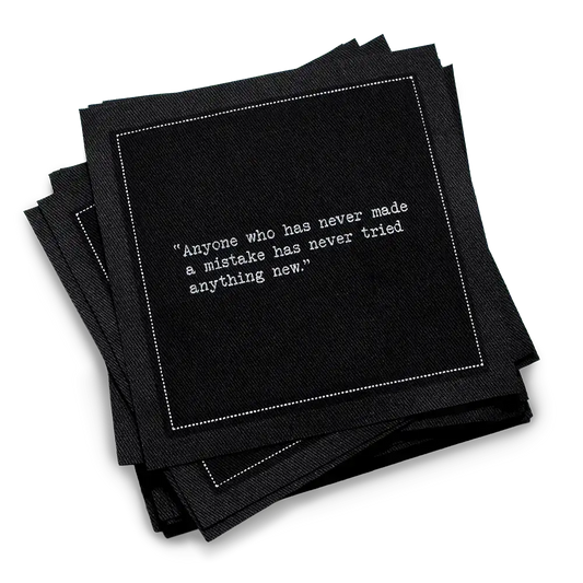 Organic cotton cocktail napkin, black, with white dotted border printed with the quote "Anyone who has never made a mistake has never tried anything new," from Five Star Napkins' Einstein quote collection