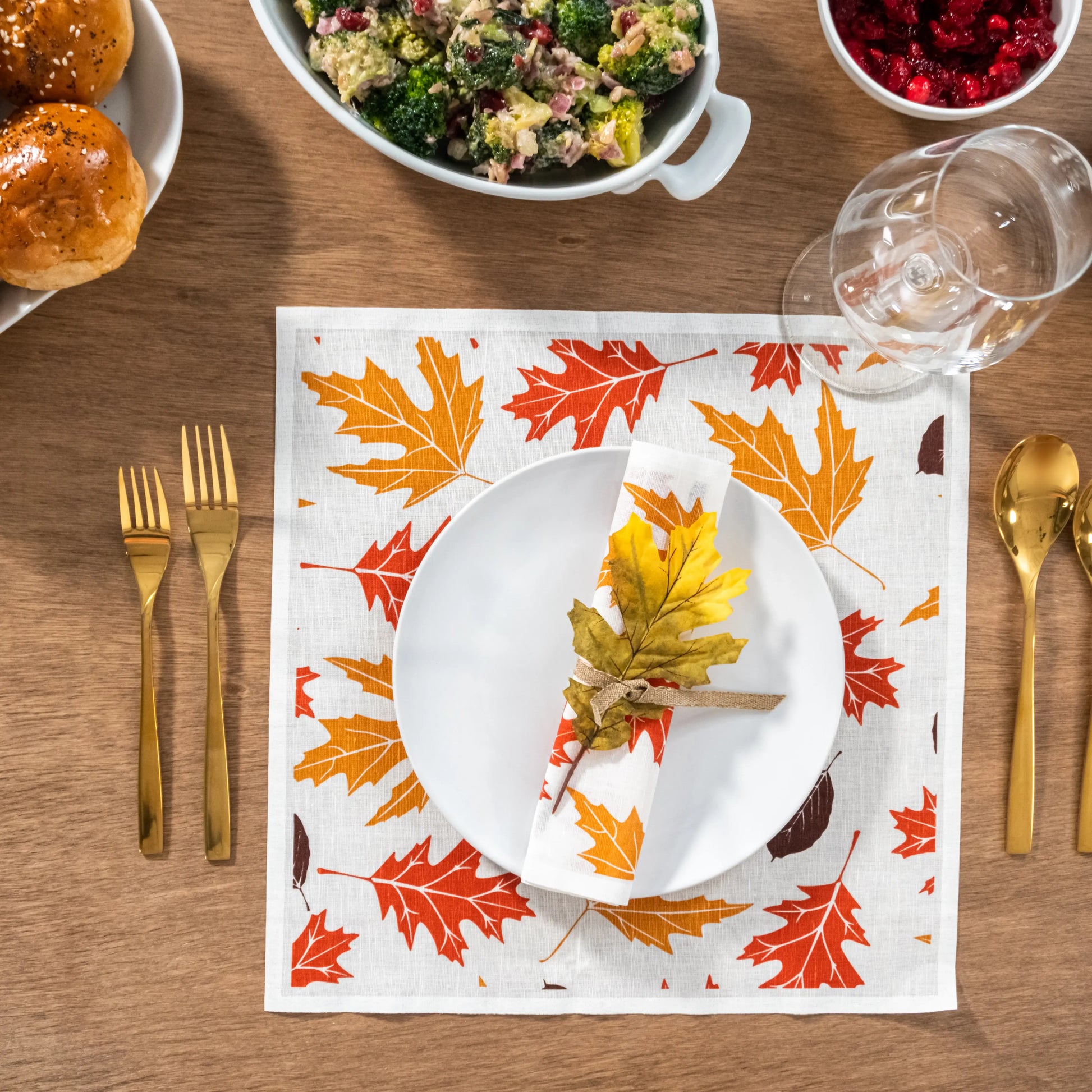 Autumn leaf print organic cotton napkin and placemat on dining table with gold flatware