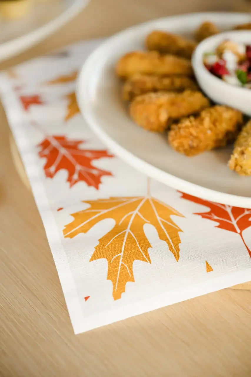 organic cotton napkin with orange and yellow maple leaf print under plate at table setting