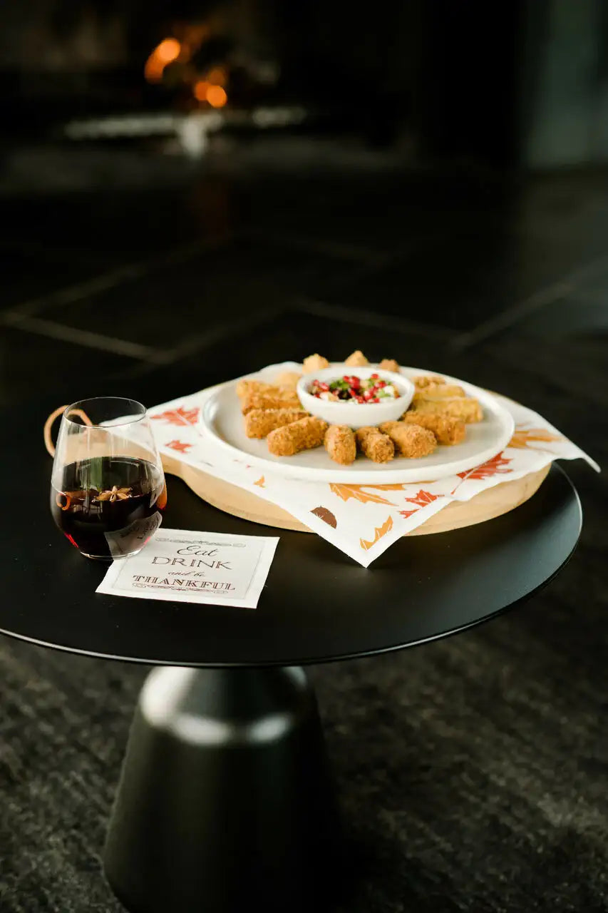 Autumn leaf print organic cotton dinner napkin set beneath appetizers and a wine glass, styled alongside an “Eat, Drink, Be Thankful” quote napkin, by Five Star Napkins.