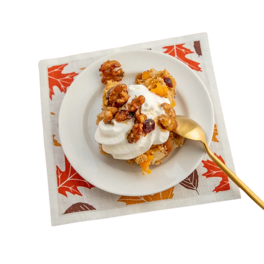 Dessert on a white plate atop a fall-themed luxury cotton cocktail napkin with gold spoon
