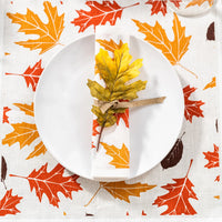 Autumn leaf print luxury organic cotton napkin on white plate, fall placemat underneath.