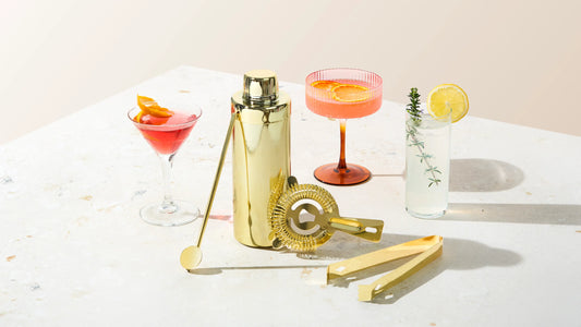 Gold cocktail shaker set styled with a martini, cosmopolitan, and gin and tonic, by Five Star Napkins.